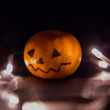 Image of a satsuma with a Halloween face drawn on