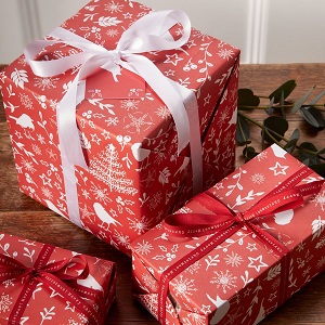 Image of recycled wrapping paper with festive white print on a red background, to help you be more eco friendly at Christmas