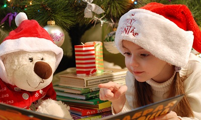 Image of a girl reading a book in front of a Christmas tree