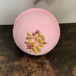 Image of a sweet scented indulgent and handmade bath bomb with sugar balls. These are wrapped in a plant-based cellulose wrapper (not plastic).